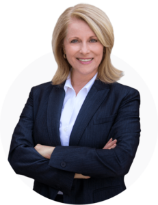 Older professional looking woman, smiling with her arms crossed, looking into the camera.